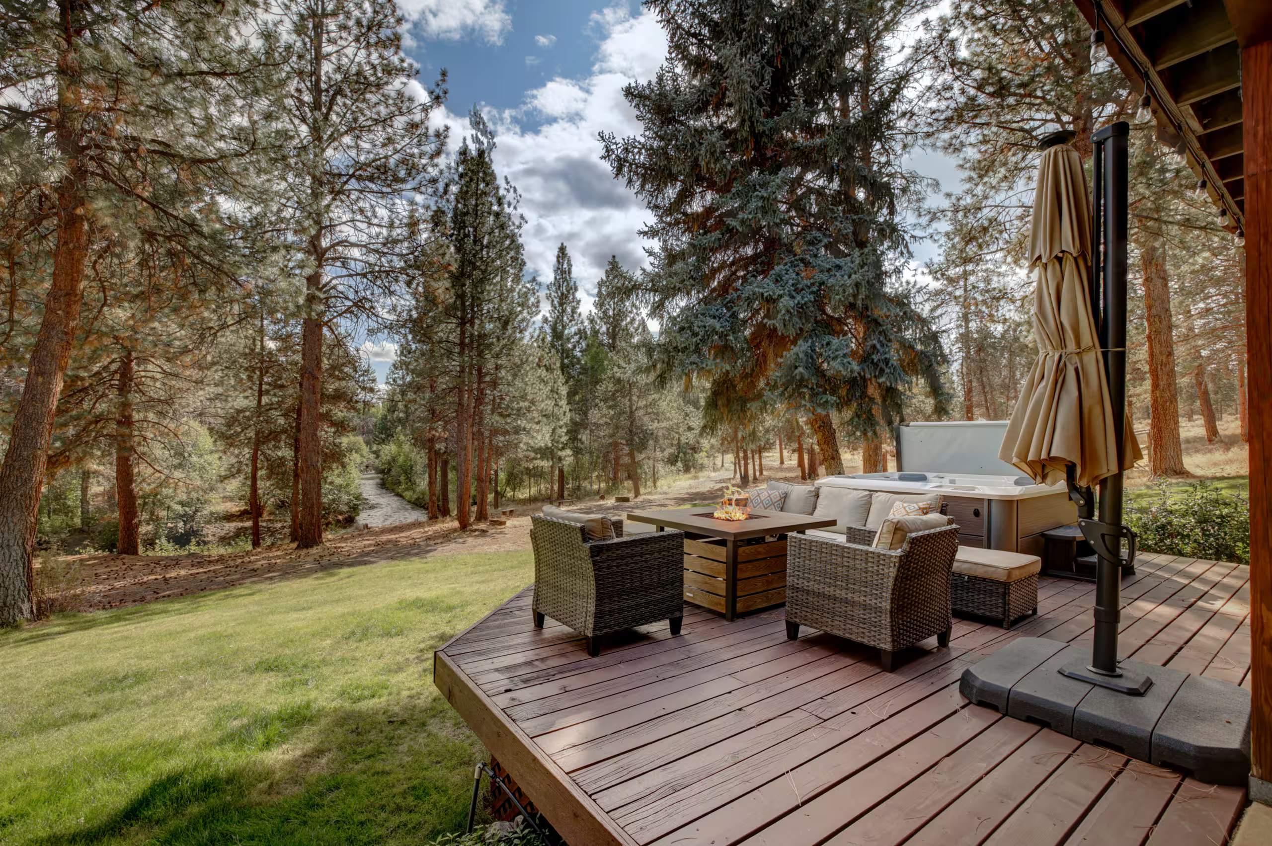 Wooden deck with wicker lounge chairs and a fire table under tall ponderosa pines