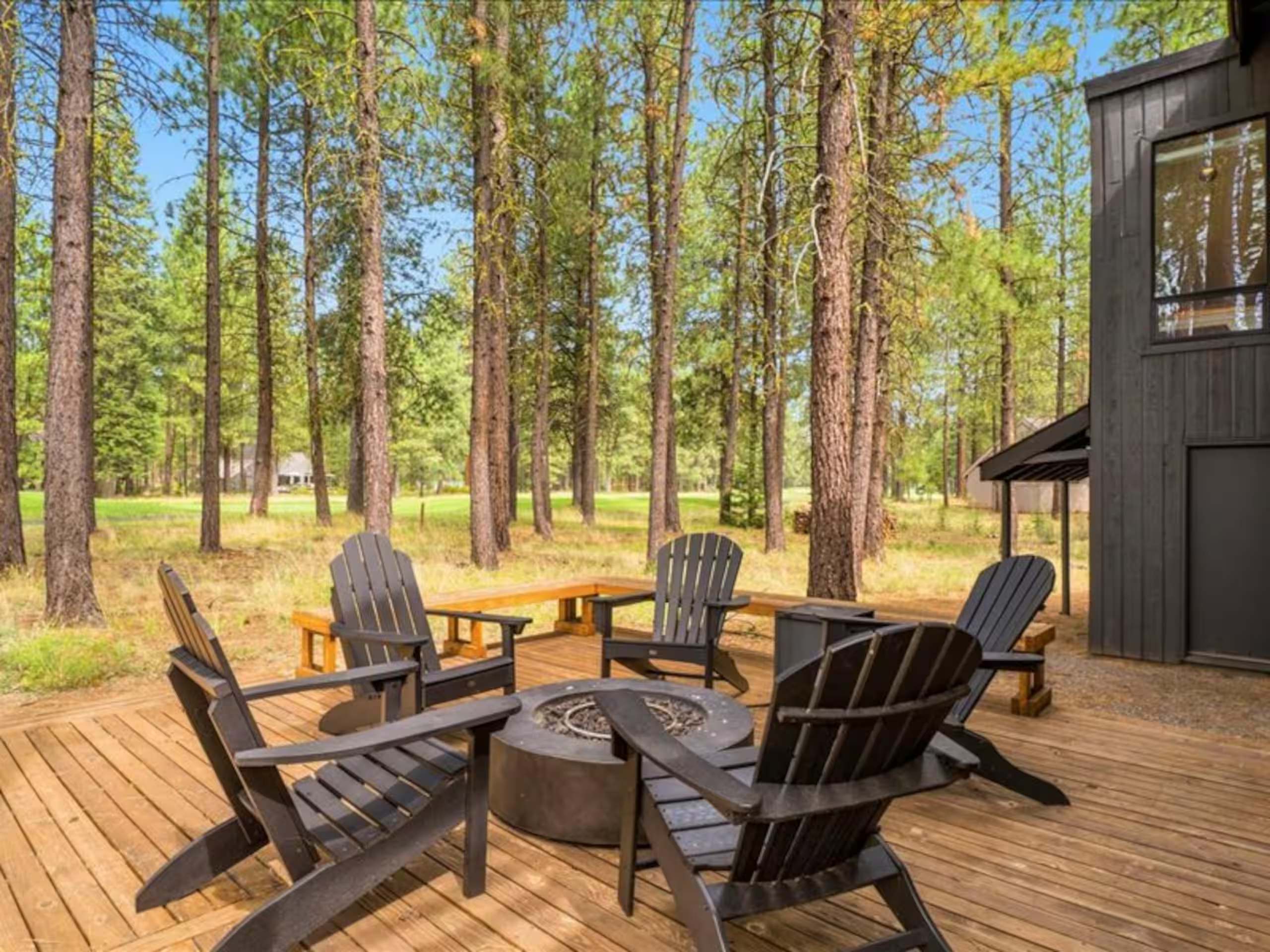 Adirondack chairs gathered around a fire pit on a cedar deck among tall ponderosa pines